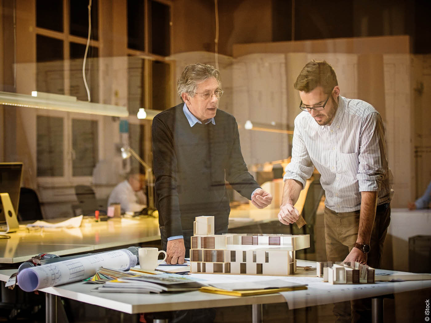 Zwei Architekten besprechen ein Gebäudemodell am Arbeitstisch